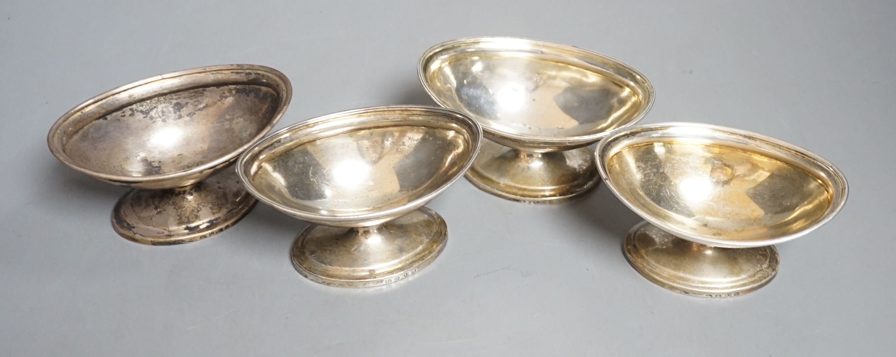 A set of four George III silver boat shaped pedestal salts, London, 1799, maker's mark rubbed, length 10cm, 345 grams.